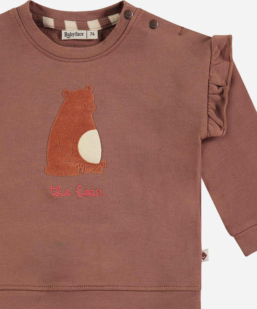 Details:&nbsp; This fashionable baby sweatshirt is made with a Bear print on the front and frills, a round neckline, ribbed arm cuffs and waistband, and push buttons on the side for easy opening. Perfect for any little one, this sweatshirt provides both comfort and style.&nbsp;
Color: Wood&nbsp;
Composition:&nbsp; 95% BCI cotton/5% elasthan &nbsp;