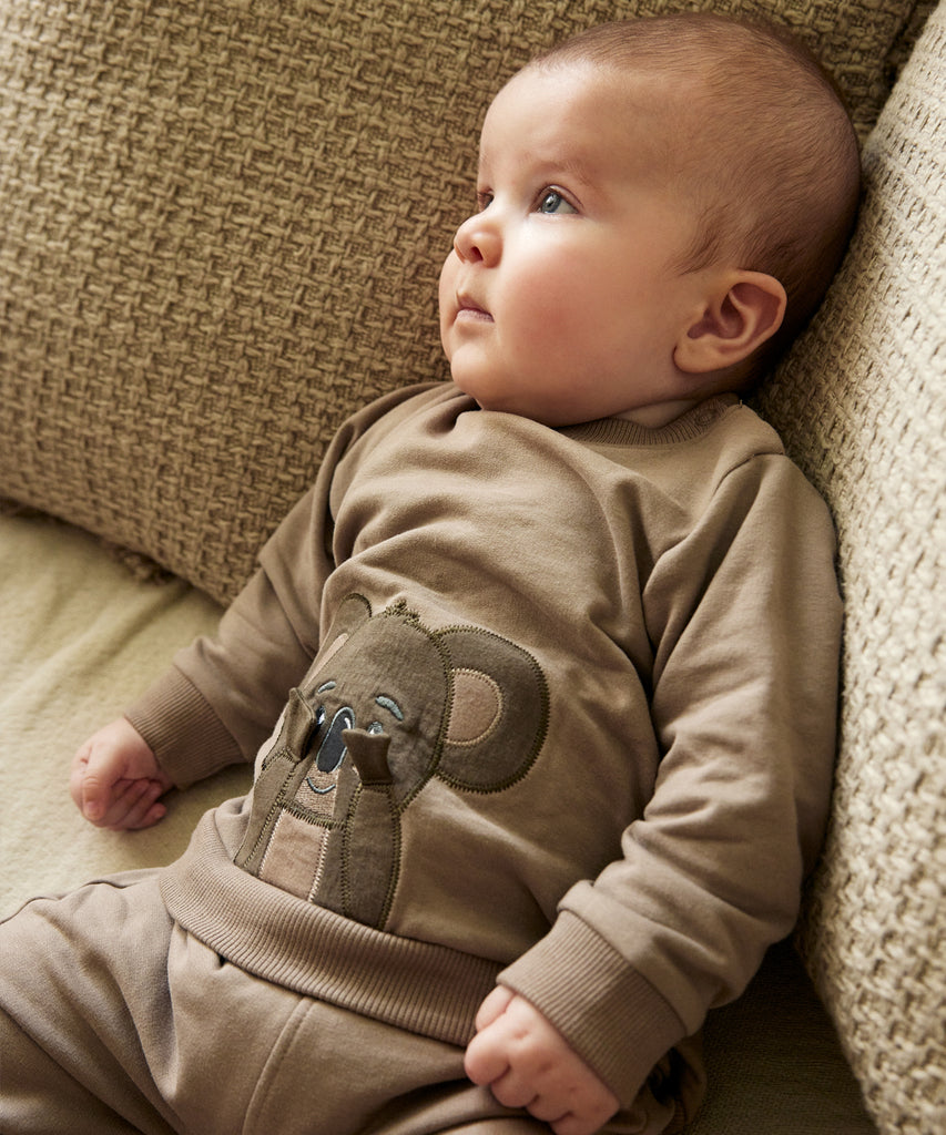 Details:&nbsp; This taupe baby sweater features an adorable koala design on the front, making it a charming addition to your little one's wardrobe. The round neckline and push buttons on the side of the collar make it easy to dress your baby, while keeping them comfortable and cozy. Perfect for any occasion.&nbsp; Color: Taupe&nbsp; Composition:&nbsp;Organic Sweat Brushed 95% Cotton/ 5% Elastane&nbsp;