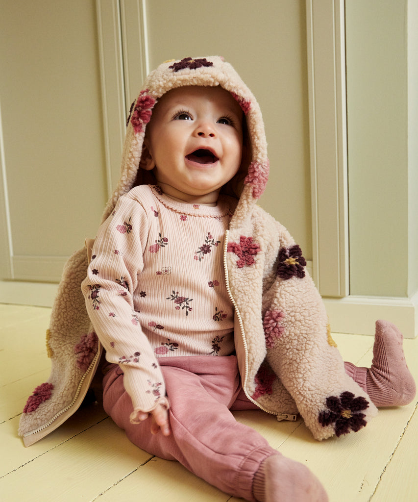 Details: &nbsp;This baby hooded teddy jacket features an all over print of Flowers and a convenient zip closure. Keep your little one warm and stylish with this cozy and cute jacket. A must-have for any fashionable baby's wardrobe. Color: Sandshell&nbsp; Composition:&nbsp; 100% Polyester &nbsp;