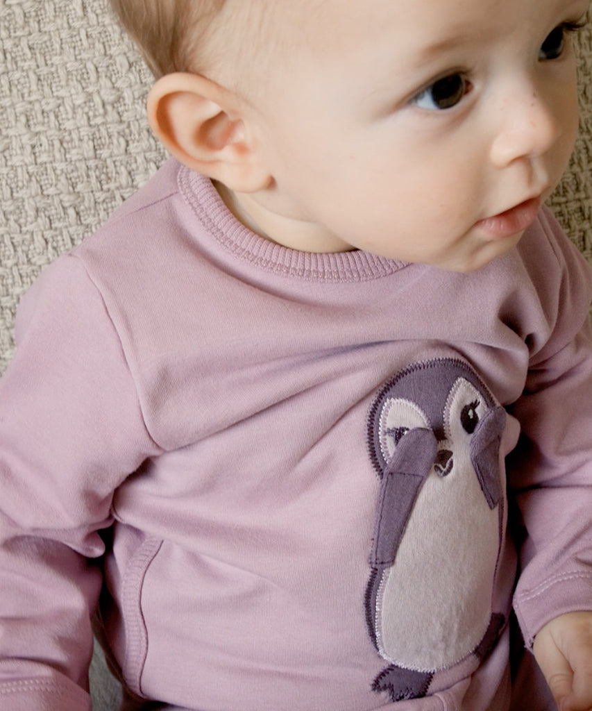 Details:&nbsp; This dawn pink baby sweater features an adorable Penguin design on the front, making it a charming addition to your little one's wardrobe. The round neckline and buttons on the back make it easy to dress your baby, while keeping them comfortable and cozy. Perfect for any occasion.&nbsp; Color: Dawn pink&nbsp; Composition:&nbsp; Organic Sweat Brushed 95% Cotton/ 5% Elastane &nbsp;