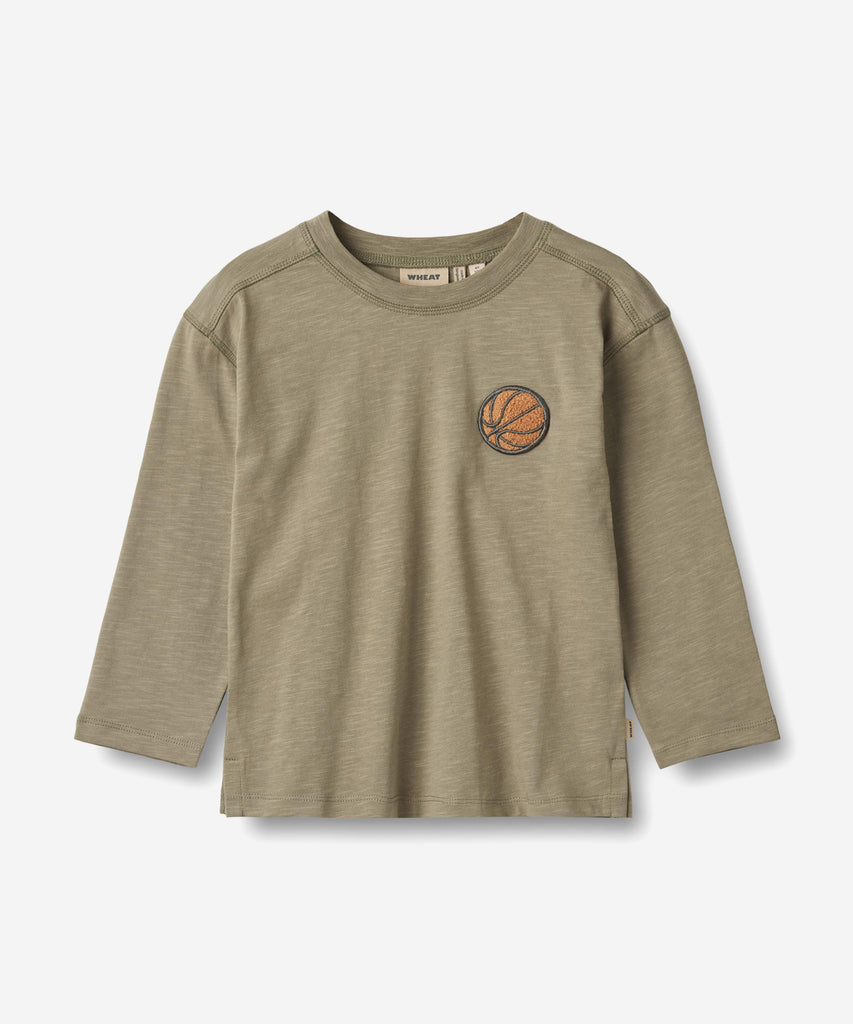 Details:
Long-sleeved t-shirt in soft organic cotton for the junior child.
- Loose fit
- Flatlock details at shoulders and armholes
- slit at side seam
- Small embroidery badge at chest - basket ball
Wheat's T-shirts are a true essential in your child’s wardrobe, as the T-shirts are soft and comfortable for your child to wear. The T-shirts are available in beautiful colours and hand drawn prints, which are made by Wheat's in-house design team. They can easily be styled with pair of trousers or a skirt, and 